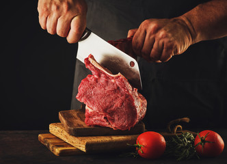 Male butcher cuts raw beef meat.