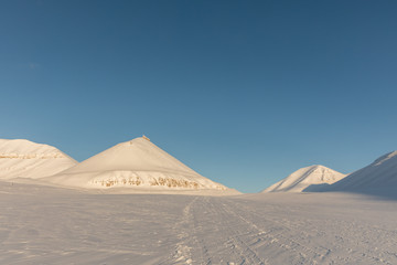 Snowmobile tracks in arctic winter landscape with snow covered mountains on Svalbard, Norway