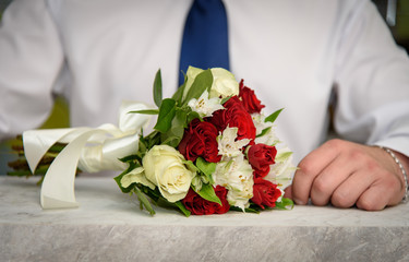 Wedding bouquet of roses on the table, against the background of a man.