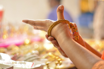 Indian woman trying bridal golden traditional wedding bangles in a shop in North India, New Delhi,...