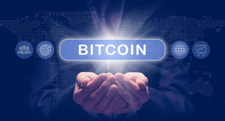 Businessmans cupped hands holding a Bitcoin business concept on a computerised display.