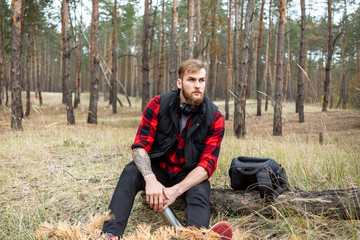 Man resting in the forest and drinking tea from the thermos.