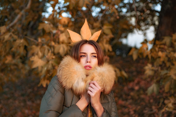 Autumnal queen with orange leaves in hair. Happy beautiful young cute woman in vegan and faux fur...