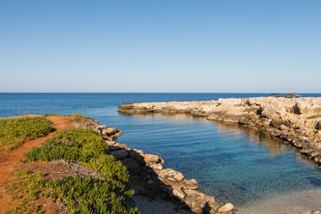Fototapeta na wymiar Small remote rocky bay in Cyprus. People enjoy azure sea.