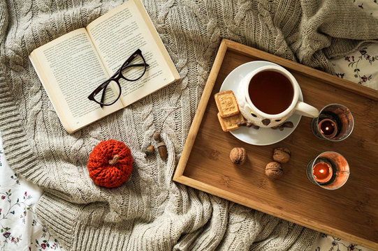 Autumn flatlay. Cup of tea with cookies, book, and decorative pumpkin 