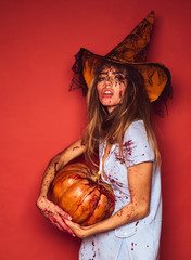 Face of Halloween girl witch on red background isolated. Witch with pumpkin. Animal instinct. Blood lust. Bloody make up.