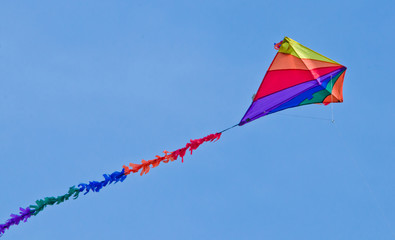 A beautiful, colourful stunt kite, in the blue sky, high up in the wind