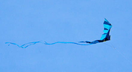 A beautiful, colourful stunt kite, in the blue sky, high up in the wind