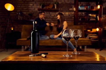 Glasses of red wine on table at home with couple