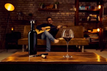Glass of red wine on table at home man sitting