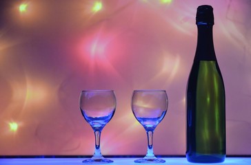 Champagne with glasses is on the table, against the background of festive blurred lights.Preparation for a festive dinner for two. On a magical evening together.