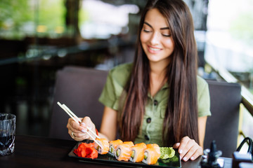 Young pretty woman eating sushi in restaurant