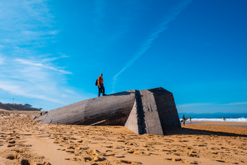 Labenne Océan, les Landes / France »; October 26, 2019: A young man climbing a Bunkers on the beach of Labenne Océan