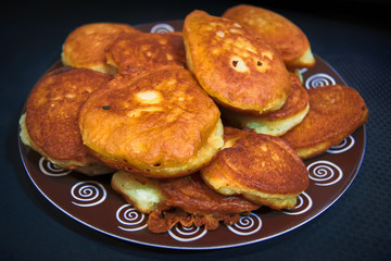 A plate with freshly baked homemade pancakes on a dark background close-up.
