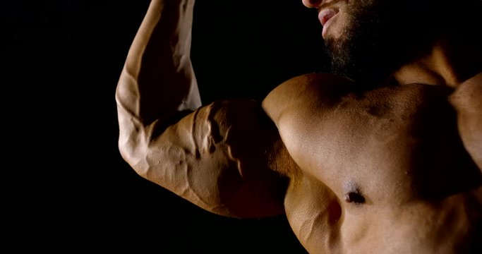 very large athletic muscular man. close-up of a strained biceps with swollen veins and a man's chest. dark key