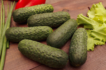 Cucumbers with lettuce and leek on a wooden table