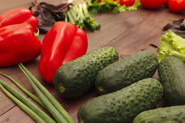Cucumbers, bellpeppers, lettuce and leek on a wooden table