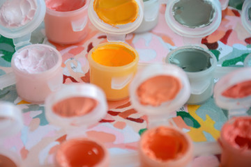 Small jars filled with paint on a painted canvas. Painting by numbers. Bright and colorful. Creative hobby. Crafts and DIY
