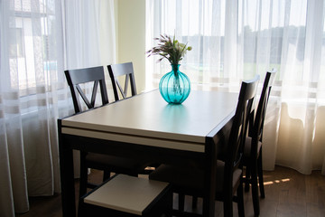 vase standing on wooden table in the kitchen Modern white u-shaped kitchen in scandinavian style. Good morning