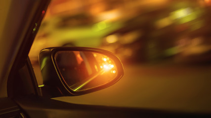 car side mirror and traffic light from vehicle headlights at night