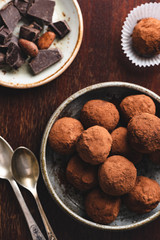 Dark chocolate truffles with raw cocoa powder on wooden background. Top view toned image