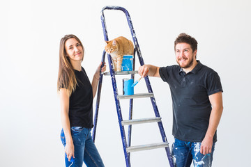 People, renovation, pet and repair concept - Portrait of funny man and woman with cat doing redecoration in apartment