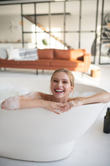 Woman feeling happy while relaxing in bath with foam