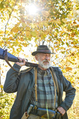 Obraz premium Older hunter spend leisure hunting. Brutal bearded man in hat, nature background.