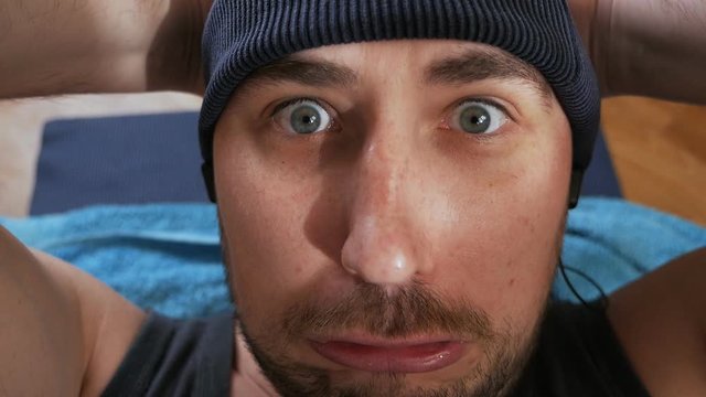 Nerd man is doing dynamic abdominal crunches exercises laying on the mat at home. Sport humor concept