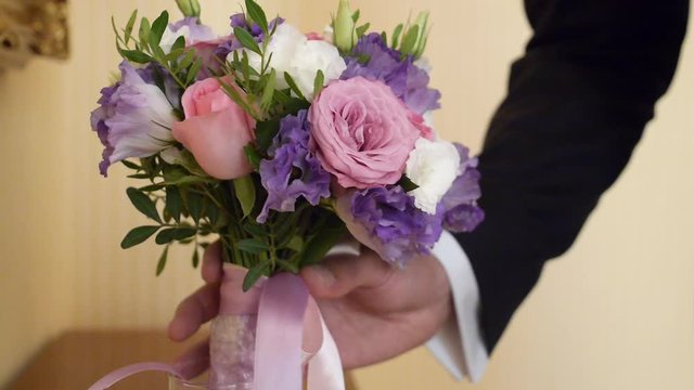 hand of the groom takes a wedding bridal bouquet from a vase in slow motion