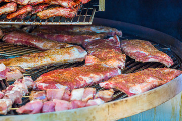 Grilled meat. Close-up cooking of large juicy pieces of raw, fat, natural, marinated pork meat, beef calves, rams on a griddle grill. A large round grill on the coals in which grilled meat