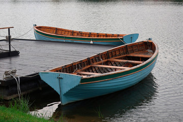 Obraz premium two boats moored at a boardwalk on the lake