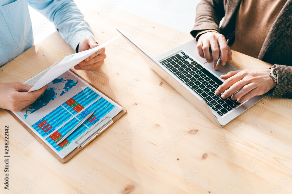 Poster financial analysts working with online data and papers by wooden table