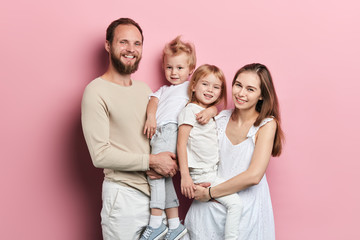 Happy young family with adoravle little daughters posing on pink background, close up portrait,...