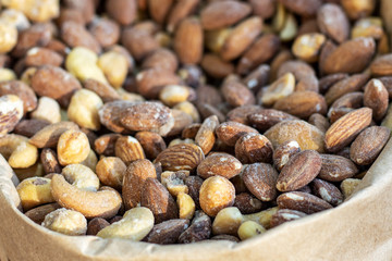 Many different salty nuts in paper bag. Peasant holiday fair. Focus in the foreground, back is blurred.