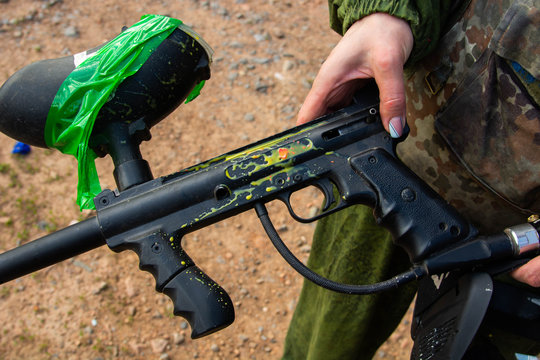 paintball sport player wearing protective mask aiming gun and shotted down with paint splash in summer