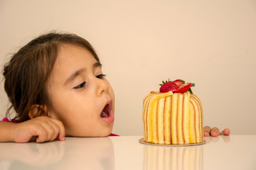 Little girl looking at cake and is surprised