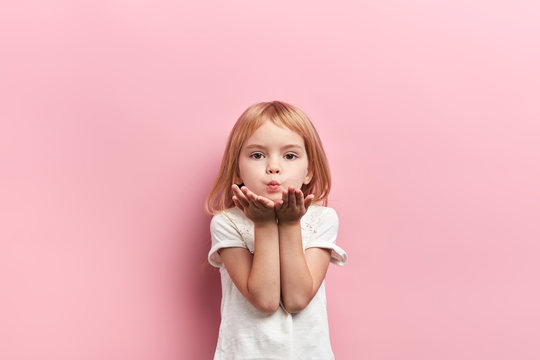 cute lovely girl sending kiss, close up portrait, isolated pink background, studio shot.