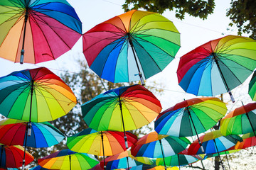 Fototapeta na wymiar Rainbow colored umbrellas hang in a public park