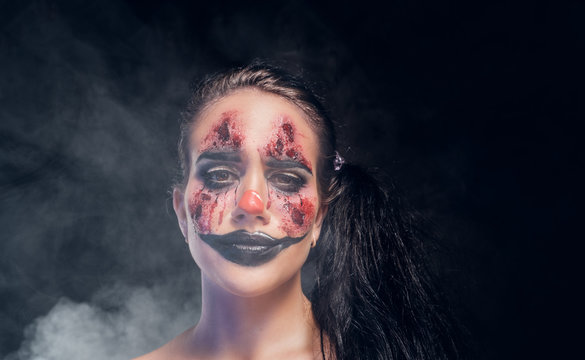 Pretty girl has very creepy makeup for Halloween in a role of creepy clown.