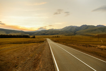 wide open road through the hills at sunset