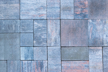 Paving slabs, stones of rectangular and square shapes of different colors laid out with patterns for equipping paths in the country as a background or texture