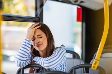 Worried young woman traveling inside of a bus. Beautiful sad woman traveling with bus, hands on...