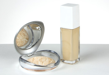 Mineral face powder and liquid foundation on a white background. Powder in a compact package with a mirror.