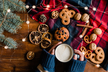 Girl holding mug with hot drink surrounded by traditional xmas food and symbols