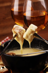 Gourmet Swiss fondue dinner on a winter evening with assorted cheeses on a board alongside a heated...