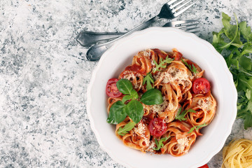 tagliatelle pasta with tomato sauce parmesan basil on rustic background