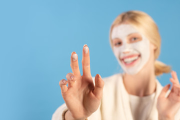 Obraz na płótnie Canvas Beautiful young woman applying moisturizing cream at face using two fingers and smile. Healthy and wellness concept. Blured healthy girl doing skin care routine.