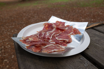 SPANISH SERRANO HAM PLATE, CUT IN FINE LINES ON AN AGED WOODEN TABLE
