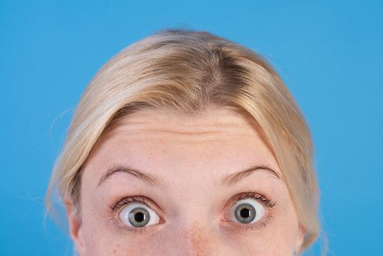 Surprised Young Blonde Woman With Blue Eyes And Thin Brows Over Bright Blue Background. Selfcare And Beauty Concept. Close Up Portrait Of Shoked Blonde Girl.